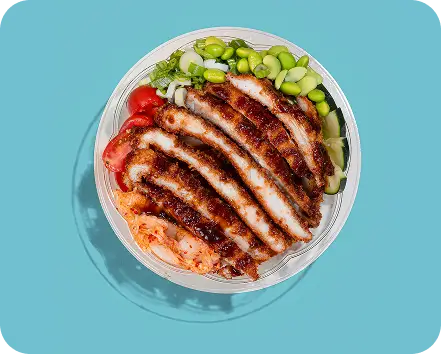 Chicken Katsu Poke Bowl with kimchi, edamame, cucumber, and tonkatsu sauce on a turquoise background.