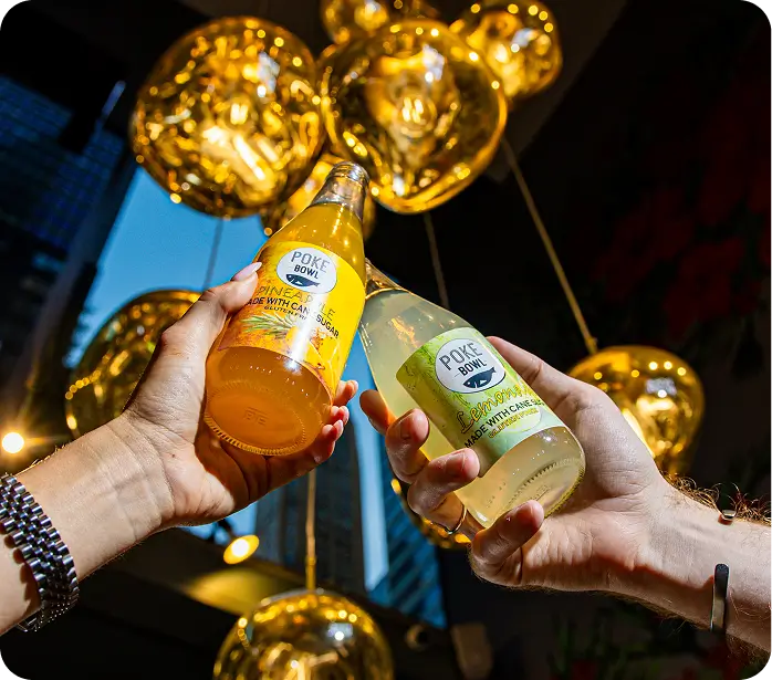 Refreshing drinks at Poke Bowl Theater District NYC, celebrating Hawaiian flavors under golden lights.