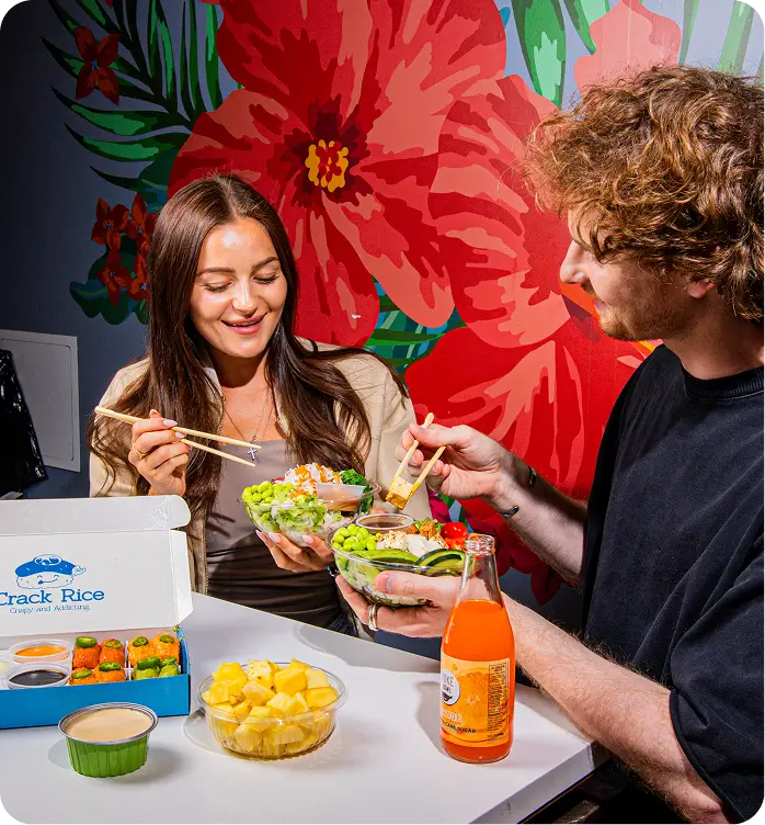 Couple enjoying Hawaiian poke bowls at NYC's Poke Bowl restaurant, set against colorful floral wall art.