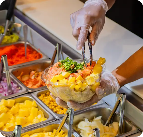 Fresh poke bowl preparation at Bryant Park's Poke Bowl NY, featuring mango, greens, and vibrant ingredients.