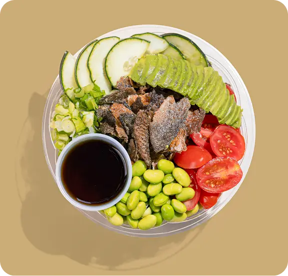 Modern Asian plant-based poke bowl with avocado, edamame, tomatoes, and sauce at Chinatown NYC restaurant.