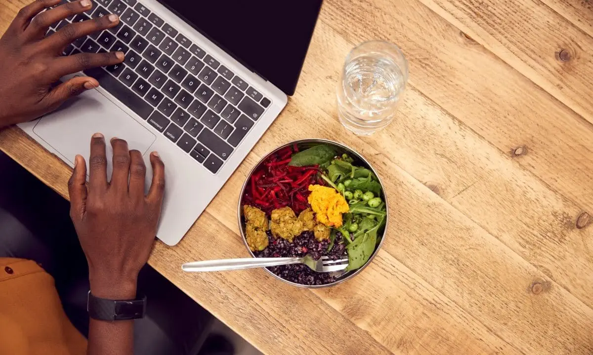 Nutritious poke bowl beside laptop, ideal for energizing office lunches and catering to diverse dietary needs.