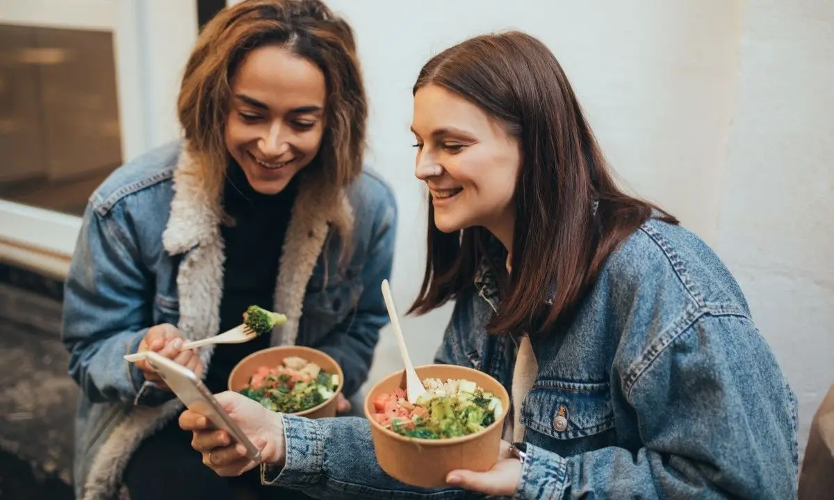 Friends enjoying modern poke bowls outdoors, showcasing cultural fusion and vibrant ingredients.